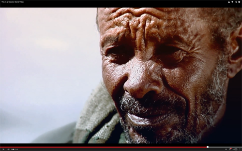 A black man with graying beard and dramatically wrinkled face looks past the viewer.