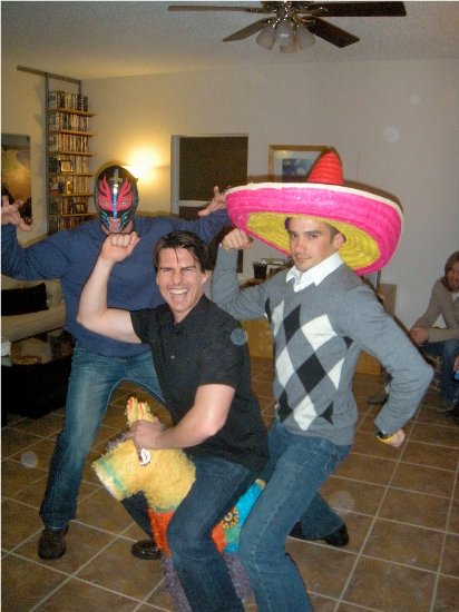 Photoshopped image of Tom Cruise at a party; he stands between two men, one of whom is wearing a sombrero, while he is posed over a pinata.