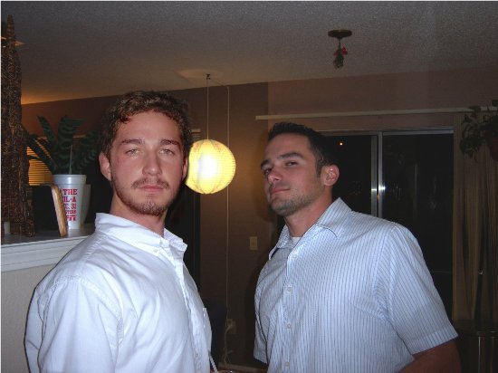 Picture of celebrity Shia LaBeouf posed next to an unknown black-haired white man.  The two are posed in the middle of a house; LaBeouf is on the left and the other man on the right of the shot.
