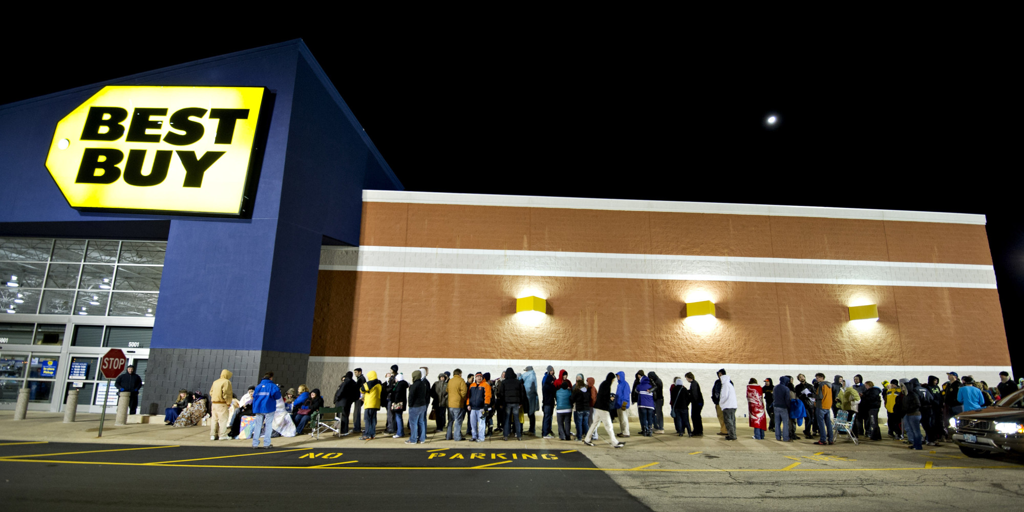 A line of people wait outside of Best Buy for the store to open