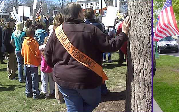 Photo of a large-ish man with a banner reading "Patriotic Resisance" across his back