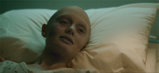 Quill's mother, resting on a pillow in the hospital. The scene is subtly tinted gold.