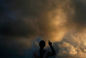 Obama speaking against sunset sky; we can only see his silhouette