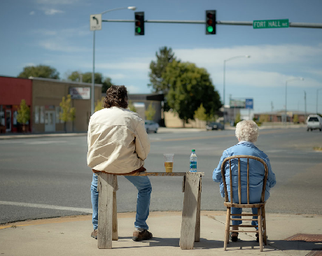 two people sitting at a stoplight with a table, as if selling something
