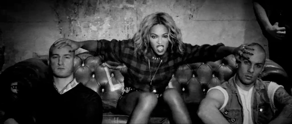 Beyonce sits on couch with hands on heads of two dudes
