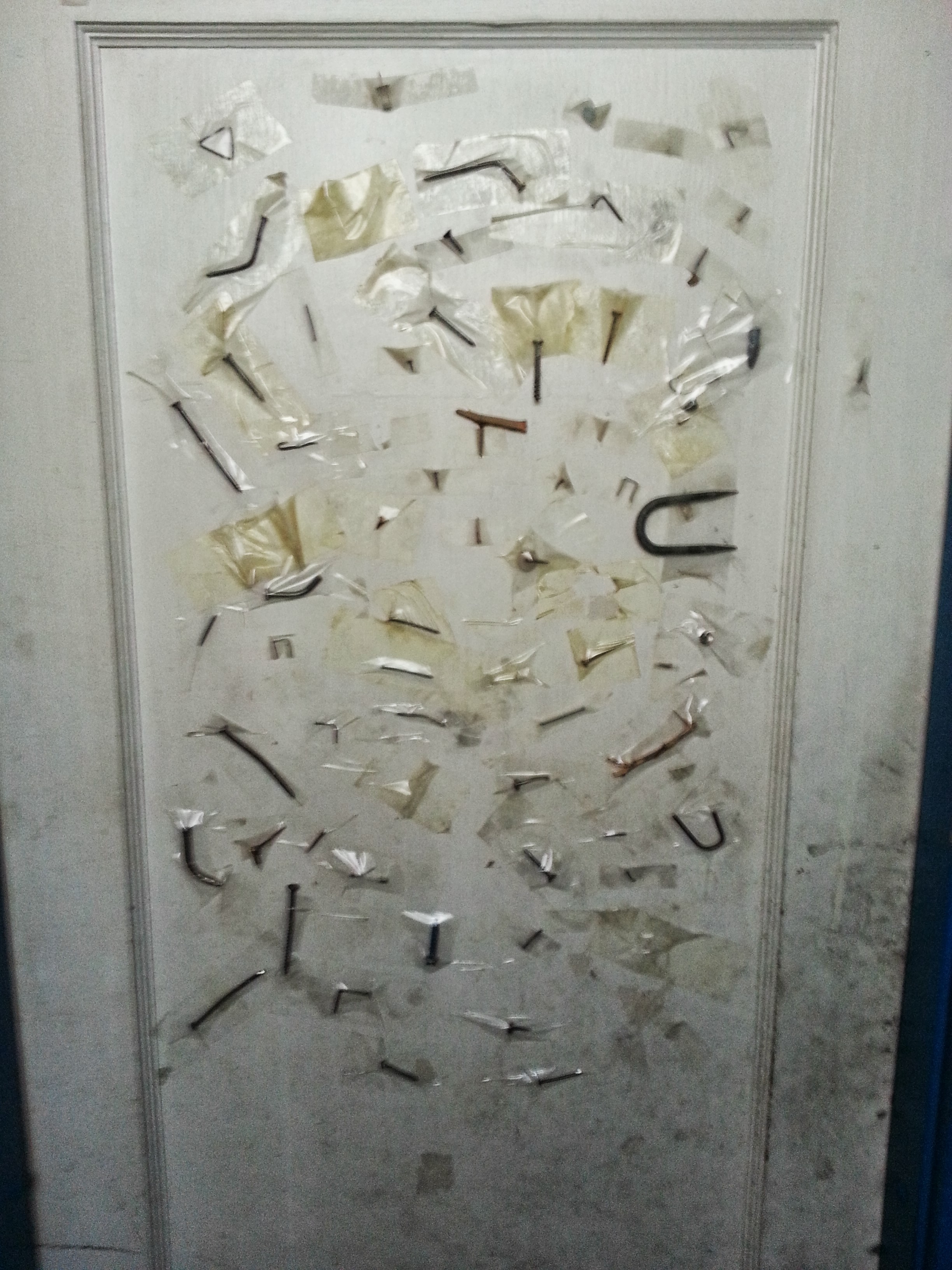a bike mechanic shop's bathroom door decorated with nails and other things that have punctured bike tires.