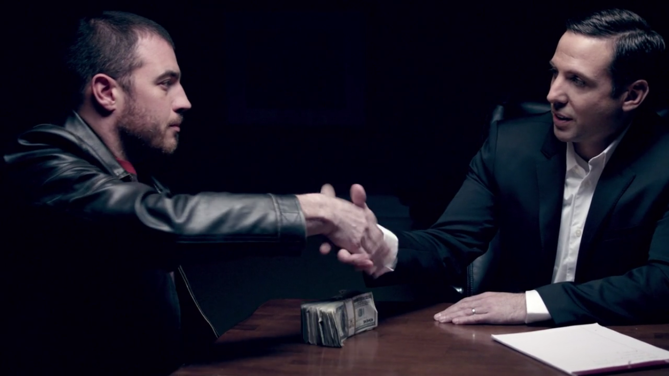 Image of Jamie Casino with a villainous client, shaking hands with money on the table between them