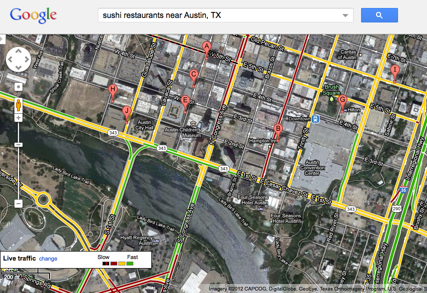Google maps "satellite view" aerial picture of downtown austin. The phrase "sushi restaurants near Austin, TX" is written in the search box across the top of the screen and the map is dotted with suggested locations. There are also colored lines indicating traffic flow.