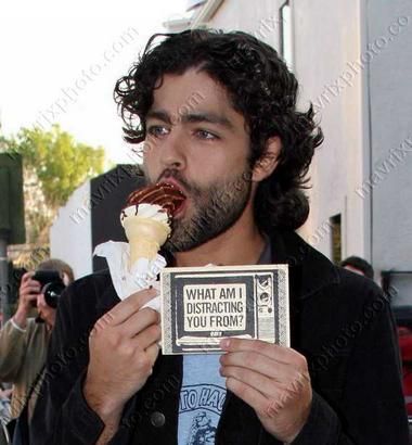 Adrien Grenier eating an ice cream cone and holding a sign that says 