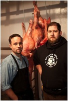 A photo of the two founders of the butcher shop Salt & Time standing in front of a pig carcass.