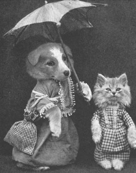 black and white photo of a dog and cat in turn of the century clothing